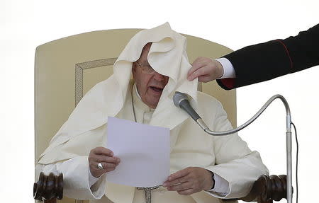 An assistant adjusts the mantle of Pope Francis as he speaks during his Wednesday general audience in Saint Peter's square at the Vatican June 17, 2015. REUTERS/Max Rossi