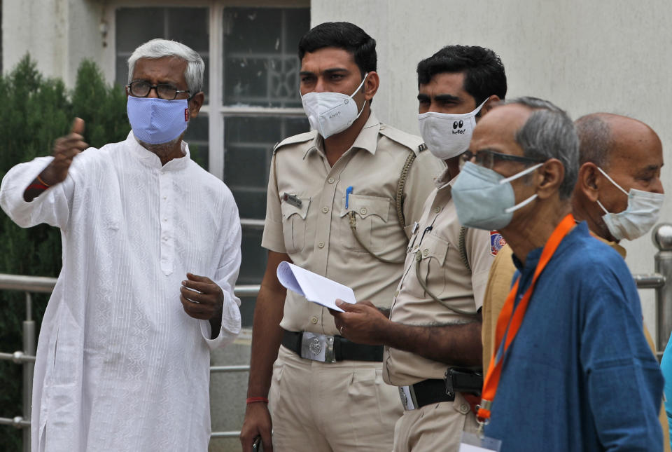 Members of the festival organizing team at the Kali Bari Hindu temple explain to policemen precautions they have taken for Durga Puja celebrations in New Delhi, India, Thursday, Oct. 22, 2020. Most of the festival festivities are being scaled down following the health officials warning about the potential for the coronavirus to spread during the religious festival season, which is marked by huge gatherings in temples and shopping districts. (AP Photo/Manish Swarup)
