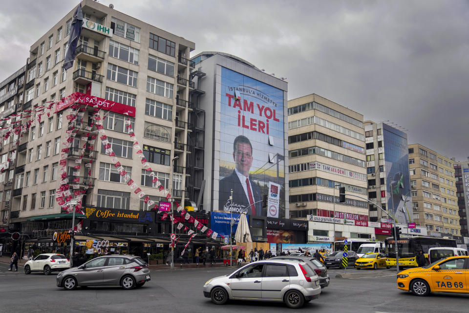 Cars drive past a giant campaign poster of Istanbul Mayor and Republican People's Party, or CHP, candidate Ekrem Imamoglu, in Istanbul, Turkey, Tuesday, March 5, 2024. On Sunday, millions of voters in Turkey head to the polls to elect mayors and administrators in local elections which will gauge President Recep Tayyip Erdogan’s popularity as his ruling party tries to win back key cities it lost five years ago. (AP Photo/Khalil Hamra)