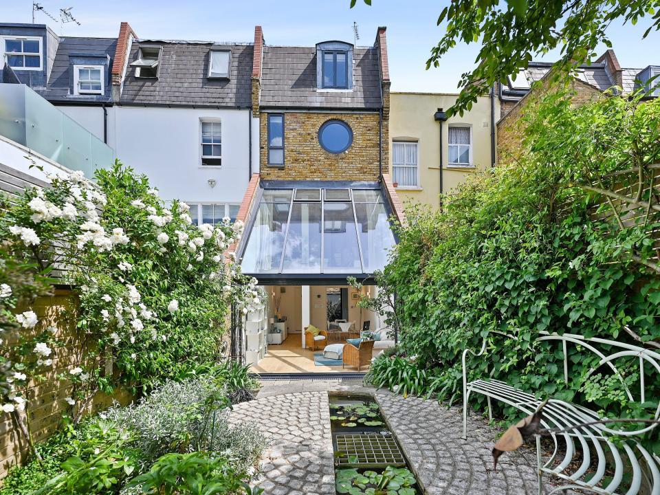 The back of a skinny home in London from the outside with greenery lining the property.