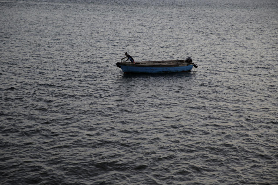 A fisherman works on his dhow moored along the coastline in Shimoni, Kenya, on Monday June 13, 2022. Artisanal fisheries on Kenya's coast say climate change, overfishing by large foreign vessels and a lack of other job opportunities for coastal communities is draining the Indian Ocean of its yellowfin tuna stocks. (AP Photo/Brian Inganga)