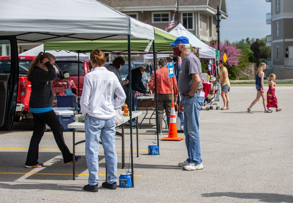 Customers shop for fresh produce and other locally sourced products at the Oconomowoc Summer Farmers Market on Saturday, May 23, 2020.