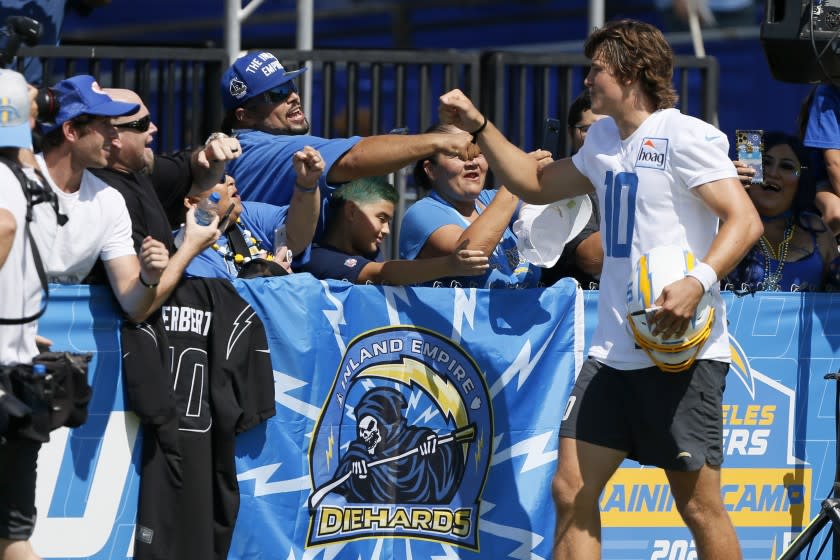 Los Angeles Chargers quarterback Justin Herbert high fives fans after practice at the NFL football team's training camp in Costa Mesa, Calif., Wednesday, July 28, 2021. (AP Photo/Alex Gallardo)