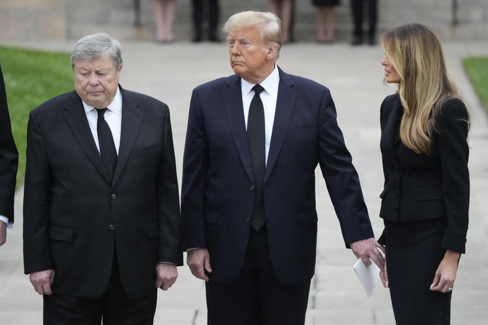 Former President Donald Trump, center, reaches for the hand of his wife Melania, as they stand with her father Viktor Knavs, left, at the end of the funeral for the former first lady's mother, Amalija Knavs, Thursday, Jan. 18, 2024, at the Church of Bethesda-by-the-Sea for her funeral in Palm Beach, Fla. (AP Photo/Rebecca Blackwell)
