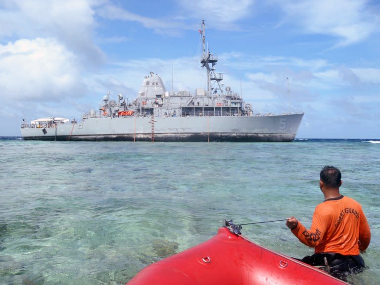 A Philippine coast guard wades towards the USS Guardian trapped on the Tubbataha coral reef, January 22, 2013 off the western island of Palawan after it ran aground on January 17