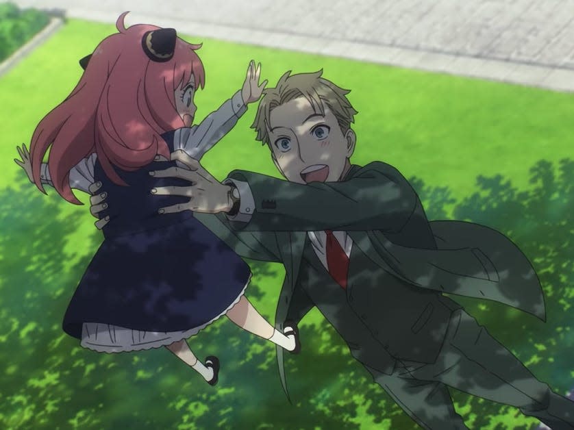 loid, a blonde man in a green suit, holding up anya, a small girl with pink hair, in spy x family