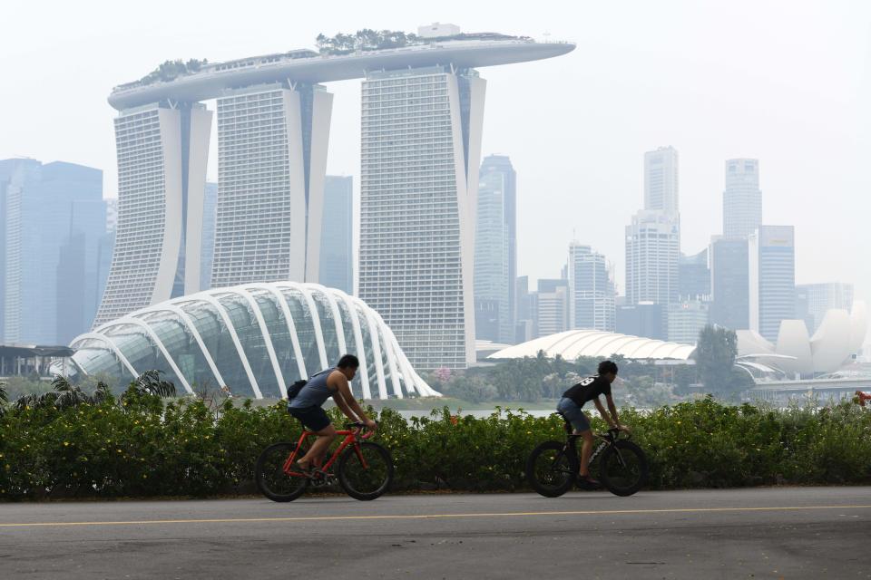 People cycle before the city skyline on a hazy day in Singapore on September 15, 2019. - Pollution from forest fires in Indonesia pushed Singapore's air quality to unhealthy levels for the first time in three years on September 14, the government said, a week ahead of the Formula One night race in the city. (Photo by ROSLAN RAHMAN / AFP)        (Photo credit should read ROSLAN RAHMAN/AFP via Getty Images)