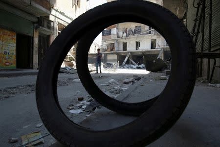 A boy walks past damaged shops and buildings in a rebel-held area of Aleppo, Syria, August 22, 2016. REUTERS/Abdalrhman Ismail