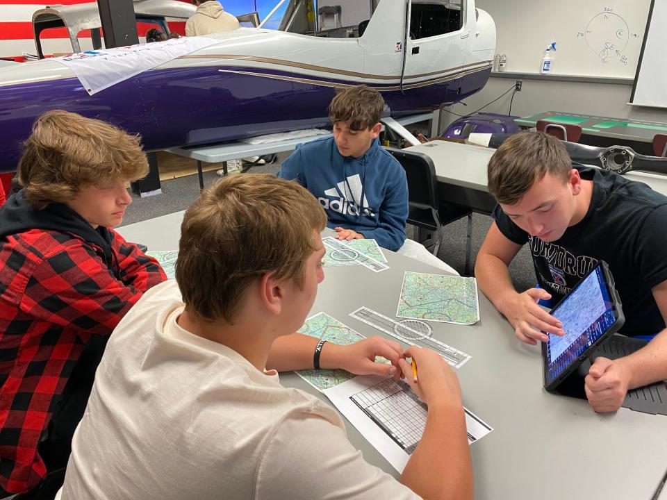 Wallenpaupack Aeronautical Science & Aviation (WASA) students devise a flight plan in their classroom. WASA students are rebuilding the airplane in back. Eric Greenberger is the teacher.