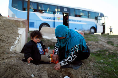 A woman, who just fled a village controled by Islamic State militants, checks her daughter as she sits in front of a bus before heading to the camp at Hammam Ali, south of Mosul, Iraq February 22, 2017. REUTERS/Zohra Bensemra