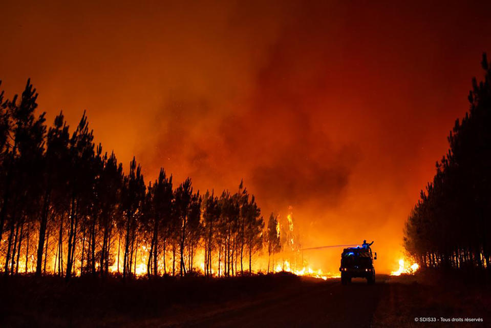 This photo provided by the fire brigade of the Gironde region SDIS 33, (Departmental fire and rescue service 33) shows firefighters tackling a blaze near Saint-Magne, south of Bordeaux, southwestern France, Wednesday, Aug. 10, 2022. (SDIS 33 via AP)