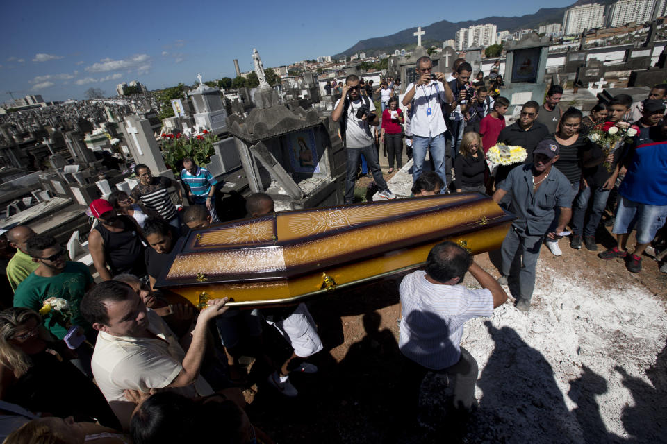 CORRECTS TO CLARIFY HOW BEZERRA DIED - Relatives carry the coffin containing the remains of Arlinda Bezerra, a resident of the Alemao slum killed during a weekend shootout, through the Inhauma cemetery in Rio de Janeiro, Brazil, Tuesday, April 29, 2014. Bezarra died when a stray bullet hit her in the stomach during a shootout between police and alleged drug traffickers. Three cars were burned in retaliation adding to the latest wave of violence in Rio's slums. Tensions have been rising in recent months amid an ambitious security push that sees officers enter slums long held by drug gangs then create permanent police posts. (AP Photo/Silvia Izquierdo)