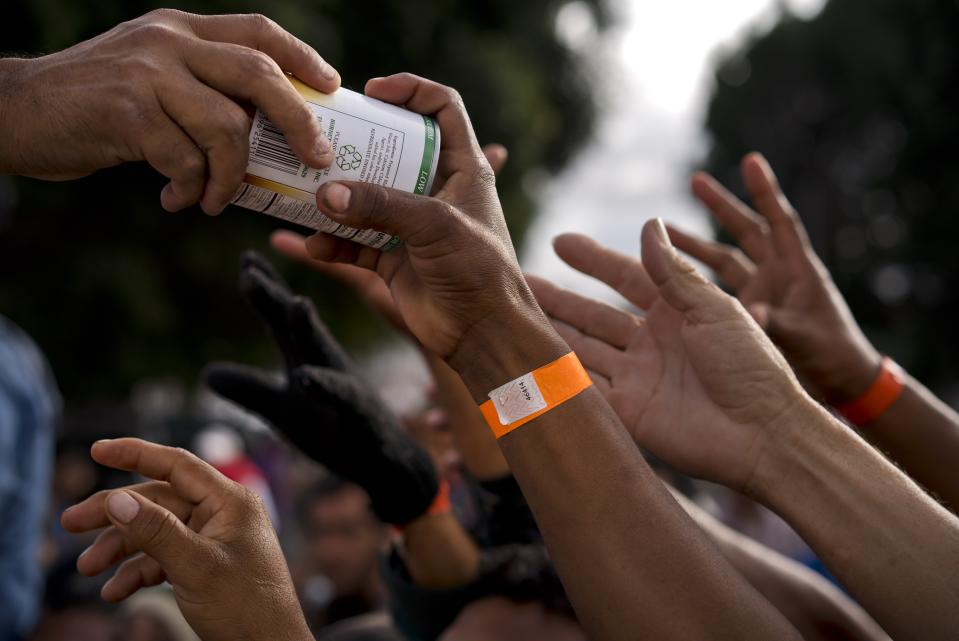 A migrant grabs a donated can of food at the Benito Juarez Sports Center serving as a temporary shelter for Central American migrants in Tijuana, Mexico, Saturday, Nov. 24, 2018. The mayor of Tijuana has declared a humanitarian crisis in his border city and says that he has asked the United Nations for aid to deal with the approximately 5,000 Central American migrants who have arrived in the city. (AP Photo/Ramon Espinosa)