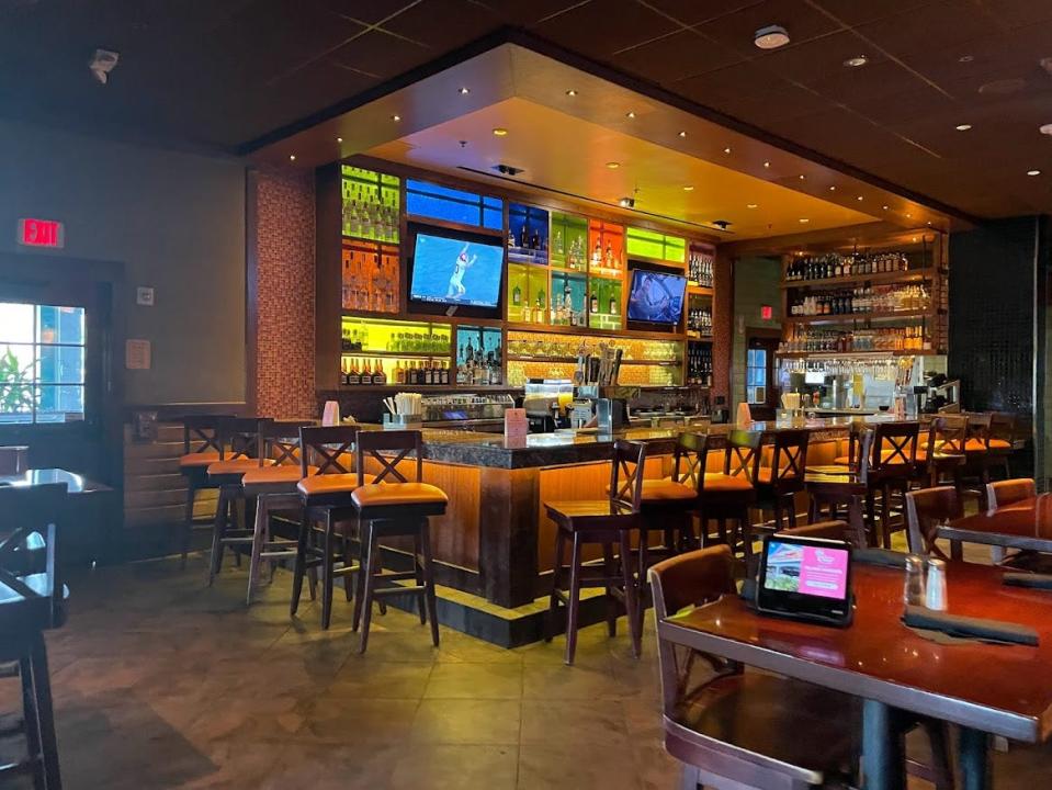 Bahama Breeze bar area with dim lighting and. TV screens behind bar