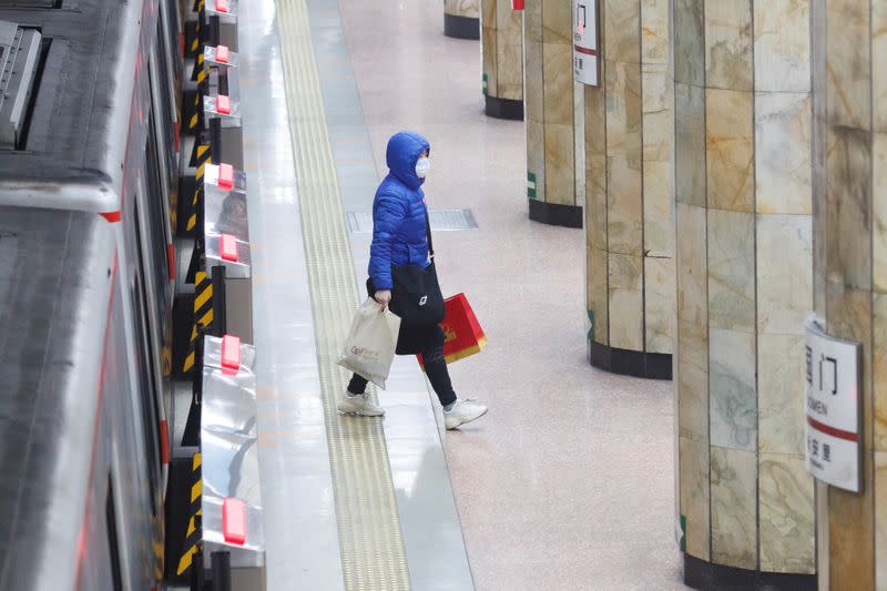 A woman wears a face mask as she leaves a subway train in Beijing as the country is hit by an outbreak of the novel coronavirus