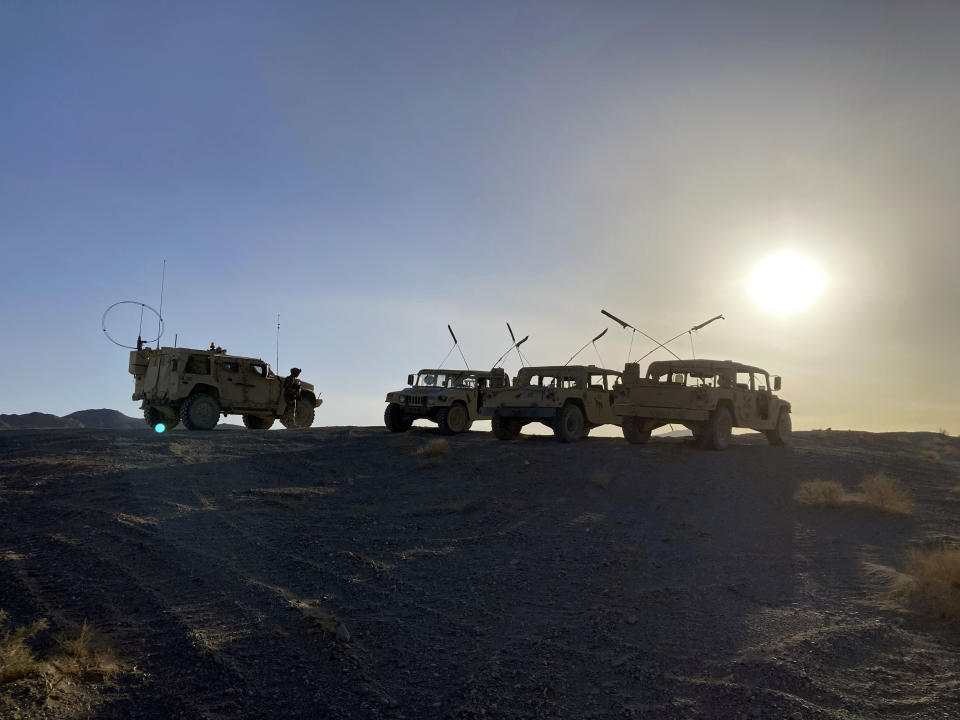 Army vehicles on the ridge, as soldiers from the 2nd Brigade, 1st Cavalry Division, prepare to attack the enemy in the town nearby, during an early morning training exercise at the National Training Center at Fort Irwin, Calif., April 12, 2022. (AP Photo/Lolita C. Baldor)