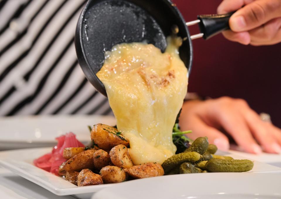 Melted Raclette cheese is poured over a mix of veggies at Pistache French bistro in downtown West Palm Beach.