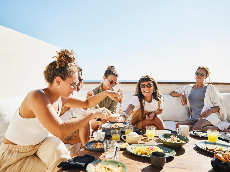 Women eating together on a sunny balcony.