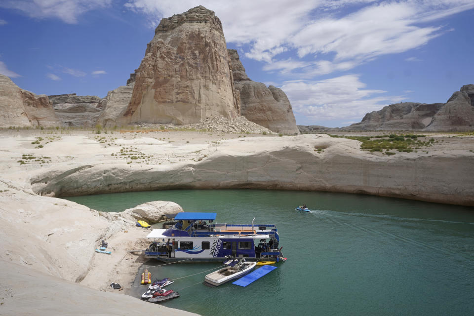 FILE - In this July 30, 2021, photo, a houseboat rests in a cove at Lake Powell near Page, Ariz. Federal water officials have announced that they will keep hundreds of billions of gallons of Colorado River water inside Lake Powell instead of letting it flow downstream to southwestern states and Mexico. U.S. Assistant Secretary of Water and Science Tanya Trujillo said Tuesday, May 3, 2022, that the move would allow the Glen Canyon Dam to continue producing hydropower while officials strategize how to operate the dam with a lower water elevation. (AP Photo/Rick Bowmer, File)