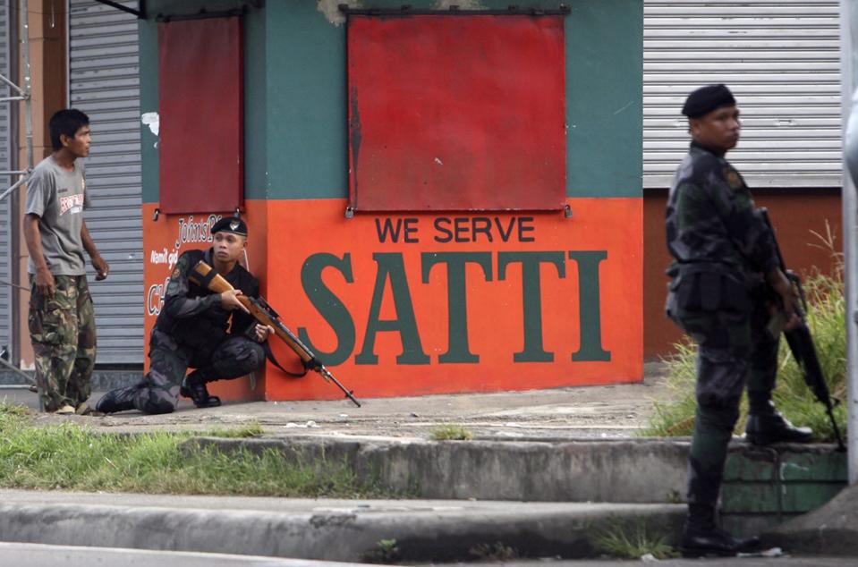 A combat police sniper (L) takes position during an encounter with rebels from the Moro National Liberation Front (MNLF) in downtown Zamboanga City