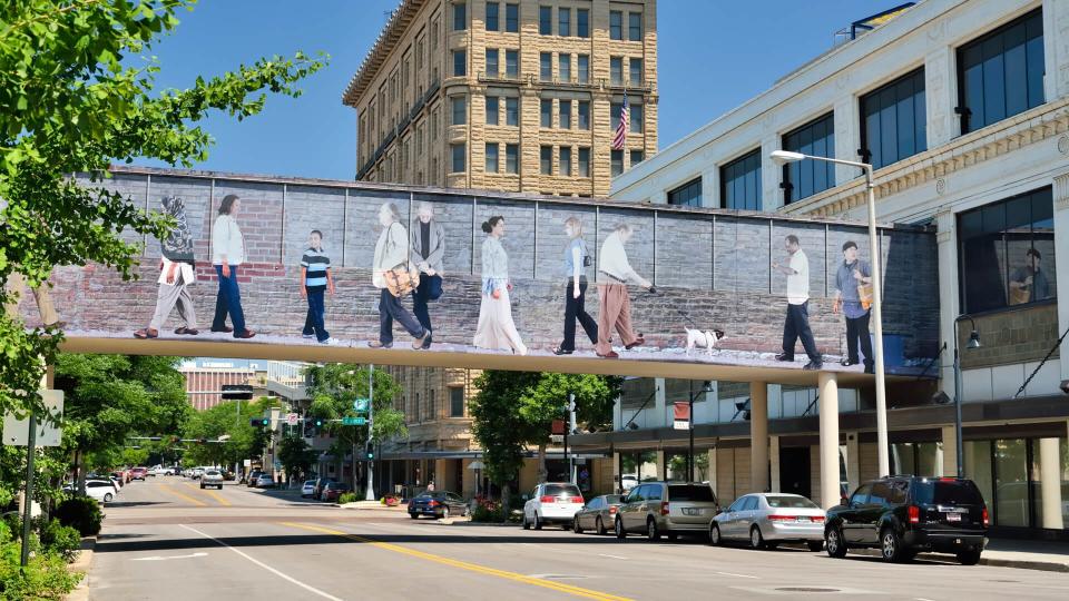 Lincoln, Nebraska, USA - July 9, 2013: People in the busy downtown area of Lincoln, the capital city of the state of Nebraska with a colorful pedestrian bridge which is part of the city's effort to make the area more appealing.