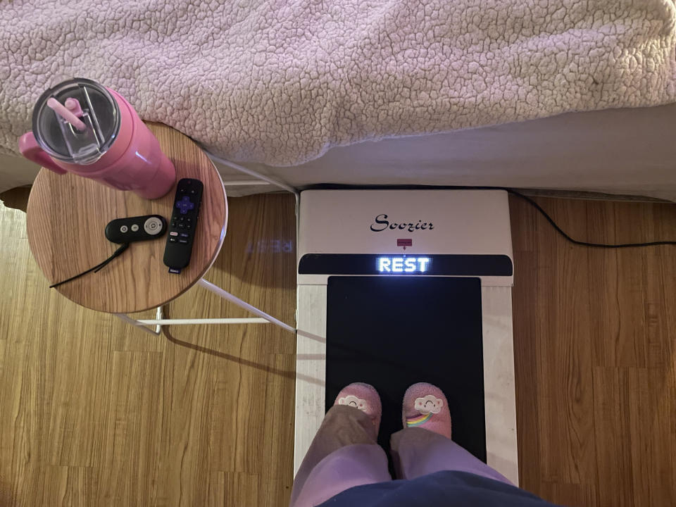 Hope Zuckerbrow, founder of the cozy cardio wellness movement, shows her workout set-up, including a walking pad, smoothie and remote control for watching television. (Hope Zuckerbrow via AP)