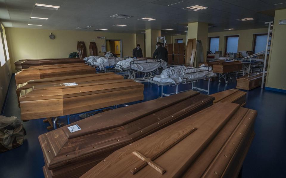 Workers stand next to coffins and remains of the coronavirus victims, in Bergamo, Italy - FOTOGRAMMA/EPA-EFE