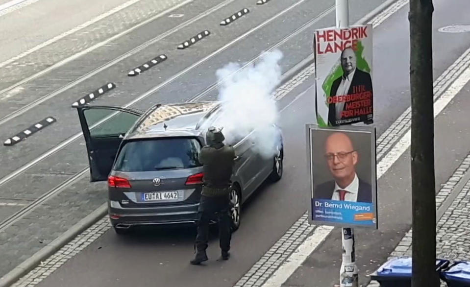 In this image taken from video made available by ATV-Studio Halle, a man shoots from long-barrelled gun, in Halle, Germany, Wednesday Oct. 9, 2019. A heavily armed assailant ranting about Jews tried to force his way into a synagogue in Germany on Yom Kippur, Judaism's holiest day, then shot two people to death nearby in an attack that was livestreamed on a popular gaming site. (ATV-Studio via AP)