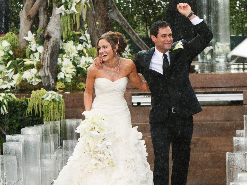 Molly Malaney, in a white strapless dress and bouquet, walks down the aisle with husband Jason Mesnick after their wedding in 2010.