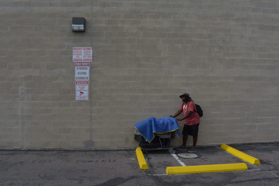 David Lane stores his belongings in a shopping cart near a security camera.