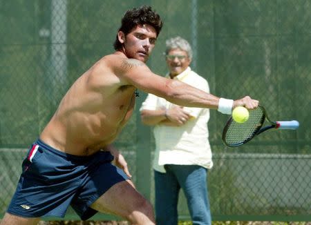 FILE PHOTO: Tennis player Mark Phillippoussis of Australia plays at the ball with the handle of his racket as his father Nick Phillippoussis looks on during practise at the Sydney International Tennis Centre in Syndney, Australia, January 11, 2004. REUTERS/Will Burgess/File Photo