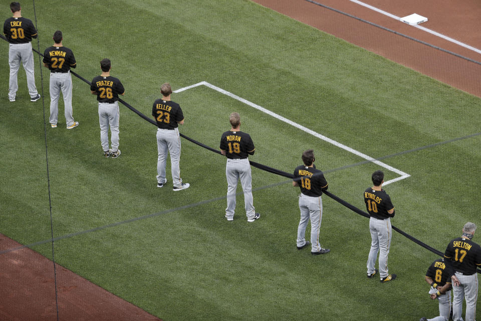 Members of the Pittsburgh Pirates hold a black ribbon in honor of Black Lives Matter before the start of a baseball game against the St. Louis Cardinals on opening day for the two teams Friday, July 24, 2020, in St. Louis. (AP Photo/Jeff Roberson)