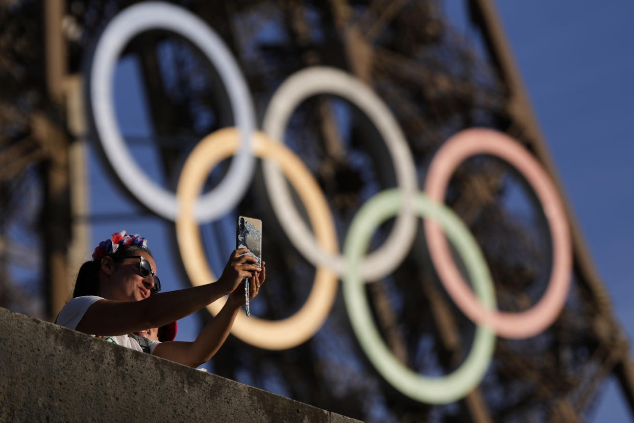 A person takes a selfie with the Olympic rings on the Eiffel Tower during the 2024 Summer Olympics.