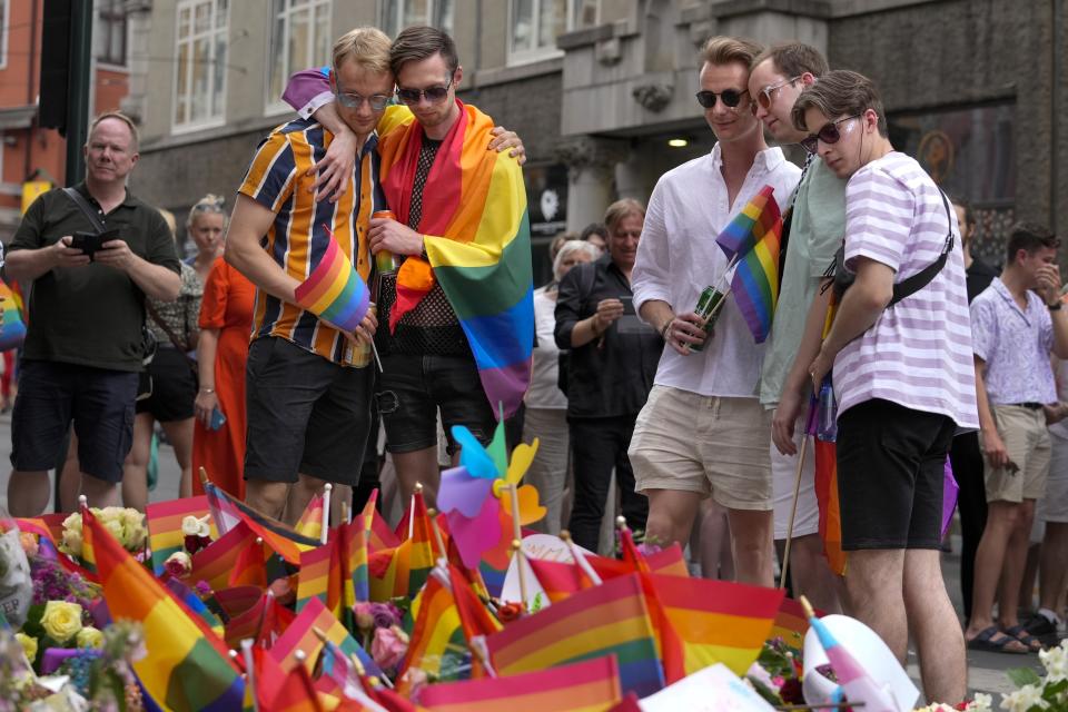 People react as they lay flowers at the scene of a shooting in central Oslo, Norway, Saturday, June 25, 2022. A gunman opened fire in Oslo's night-life district early Saturday, killing two people and leaving more than 20 wounded in what Norwegian security service called an "Islamist terror act" during the capital's annual Pride festival. (AP Photo/Sergei Grits)