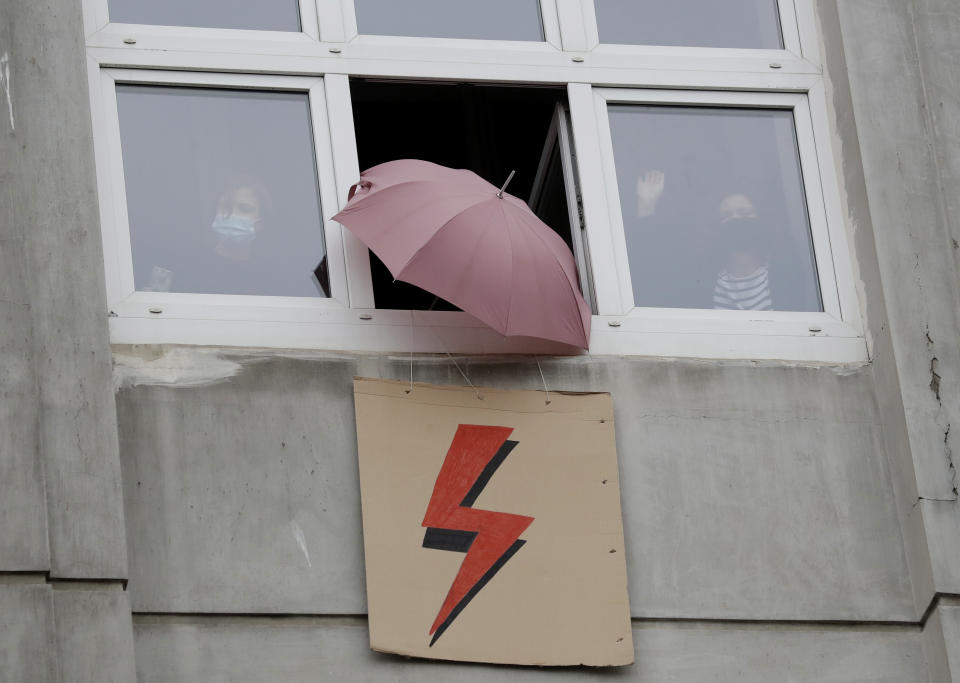 People signal support from their windows to a protest for women's rights in Warsaw, Poland, Wednesday Oct. 28, 2020. Both the umbrella and the lightning strike have become symbols of women's struggle for reproductive rights in Poland. People across Poland stayed off their jobs and crowds gathered for a seventh straight day of street protests on Wednesday in a mass outpouring of anger at a top court ruling that bans abortions in cases of congenitally damaged fetuses.(AP Photo/Czarek Sokolowski)