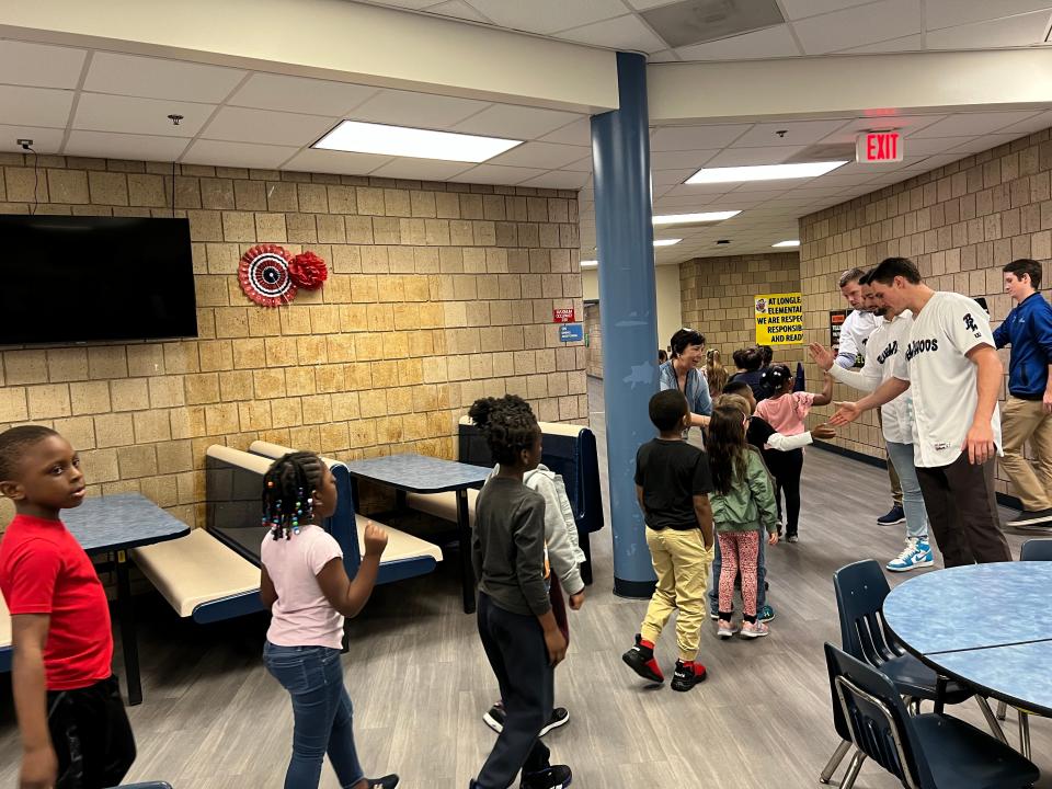 Griffin Conine high-fives young student at Longleaf Elementary School during Blue Wahoos visit Jan. 19 as part of Fish Feat event.