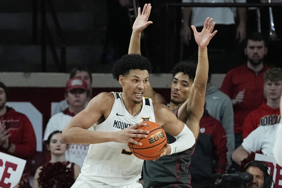 West Virginia forward Tre Mitchell, left, drives to the basket in front of Oklahoma guard Milos Uzan, right, in the second half of an NCAA college basketball game Saturday, Jan. 14, 2023, in Norman, Okla. (AP Photo/Sue Ogrocki)