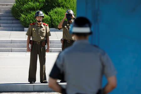 A North Korean soldier keeps watch toward the south through a binocular telescope as a South Korean soldier stands guard at the truce village of Panmunjom, South Korea, August 26, 2017. REUTERS/Kim Hong-Ji