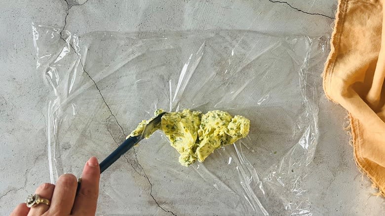 hand spreading butter on plastic with knife