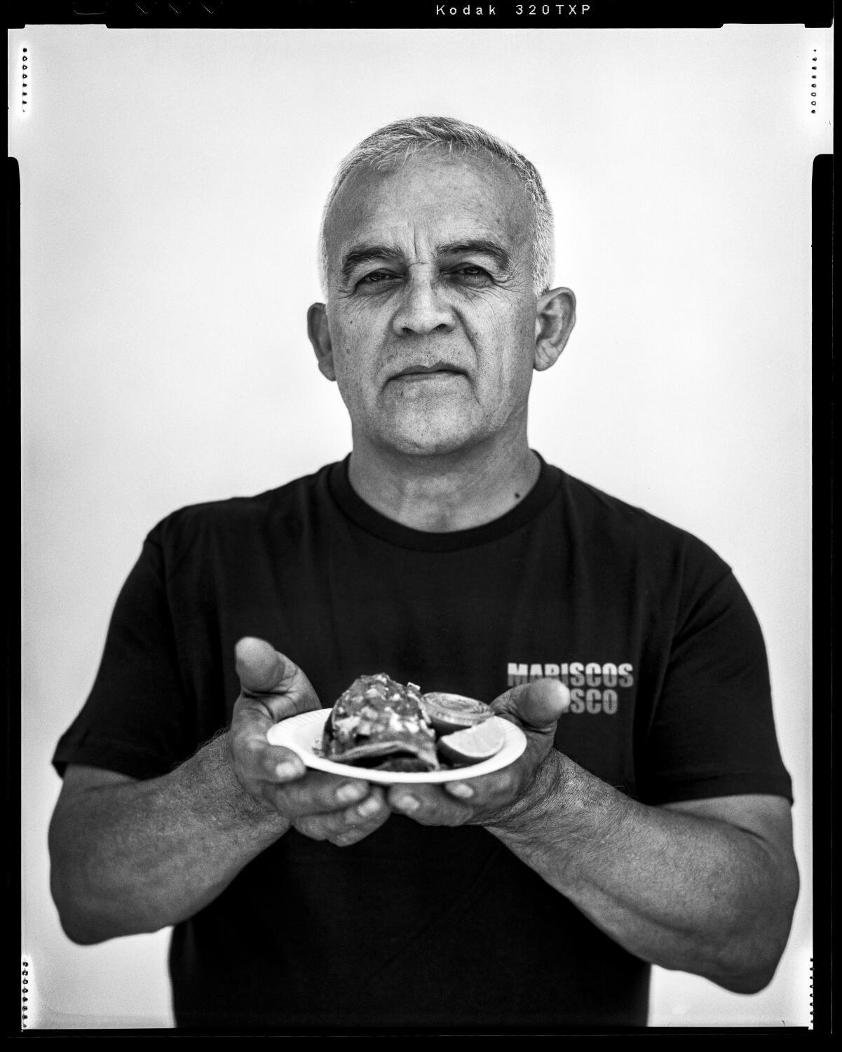 Raul Ortega holds a taco dorado de camaron outside his Mariscos Jaliscos food truck