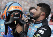 FILE- In this Feb. 17, 2019, file photo, Darrell Wallace Jr., right, prepares put on his HANS device equipped helmet before the start of the NASCAR Daytona 500 auto race at Daytona International Speedway in Daytona Beach, Fla. The lightweight head restraint co-invented by veteran sports car racer Jim Downing keeps a driver's head from snapping forward violently in a crash and has been credited with saving numerous lives in its two decades of use. (AP Photo/John Raoux, File)