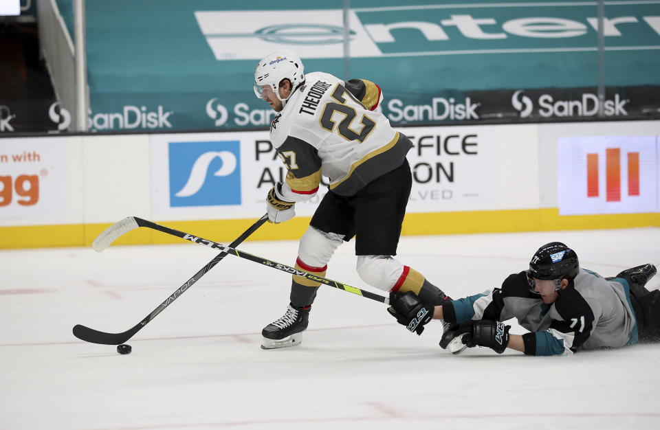 Vegas Golden Knights defenseman Shea Theodore (27) moves the puck down the ice next to a fallen San Jose Sharks defenseman Nikolai Knyzhov (71) during the first period of an NHL hockey game in San Jose, Calif., Friday, March 5, 2021. (AP Photo/Josie Lepe)
