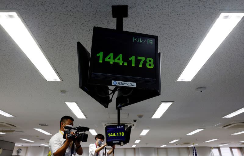 A videographer films a monitor displaying the Japanese yen exchange rate against the U.S. dollar at Gaitame.com, in Tokyo