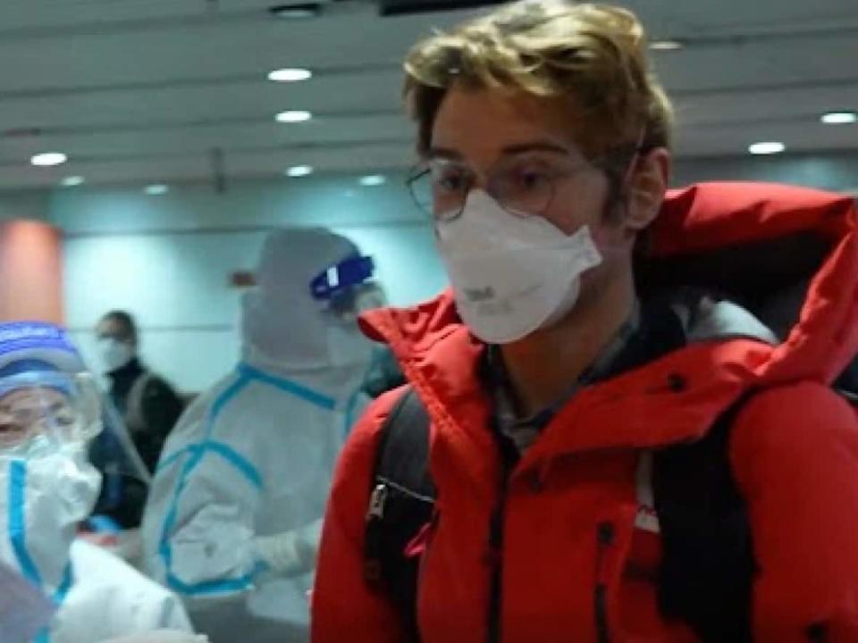 A member of the Canadian Olympic contingent makes his way through the Beijing airport after arriving for the 2022 Winter Olympics in this image from video.  (CBC News Network - image credit)