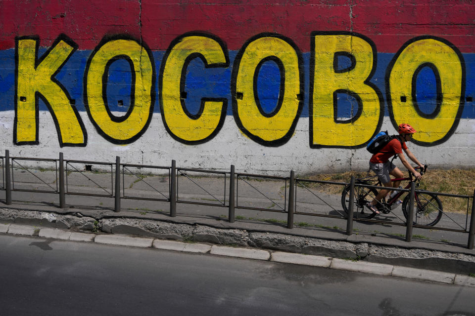 A man riding a bicycle past a mural with the writing "Kosovo" and the colours of the Serbian flag in Belgrade, Serbia, Thursday, July 13, 2023. Kosovo is a former province in Serbia whose 2008 declaration of independence Belgrade does not recognize. Most ethnic Serbs in Kosovo also have refused to acknowledge Kosovo's statehood that is backed by the United States and most EU nations but not Russia and China. (AP Photo/Darko Vojinovic)
