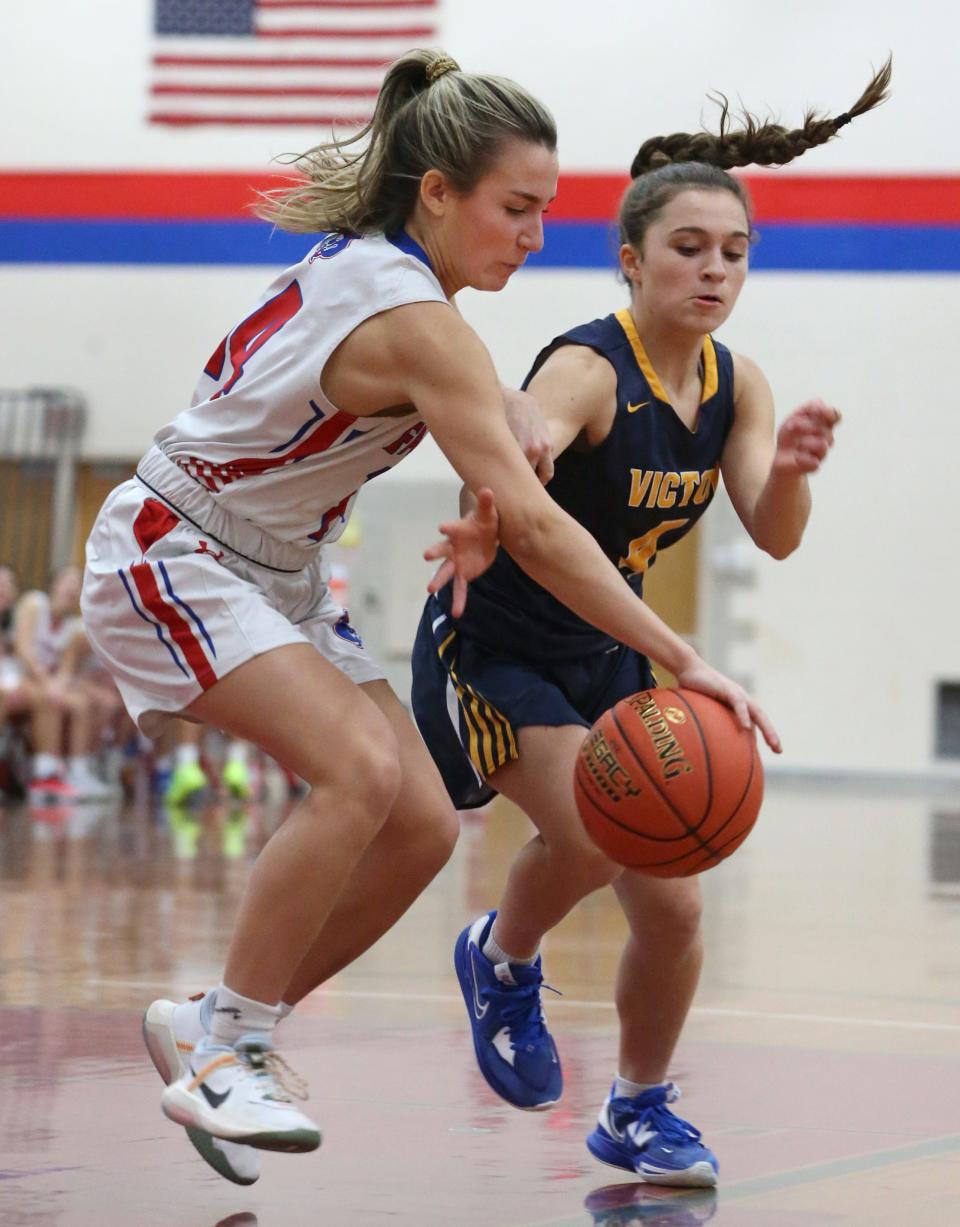 Fairport's Livea Amadori (14), left, goes for the steal on Victor's Allie Pisano (4), right, in the first half during their Section V game Friday, Dec. 9, 2022 at Fairport High School.  Fairport won the game 57-43.