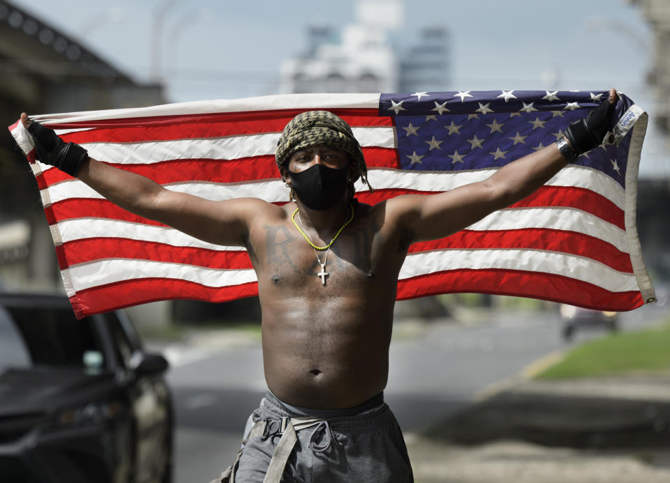 A protester holds up an American flag as about a dozen people gather on the corner of Esplanade Ave. and N. Claiborne Ave., Friday, May 29, 2020, in New Orleans, La., to protest the death of George Floyd, a handcuffed black man who died in police custody after he pleaded for air as a white police officer kneeled on his neck in Minneapolis. (Max Becherer/The Times-Picayune/The New Orleans Advocate)