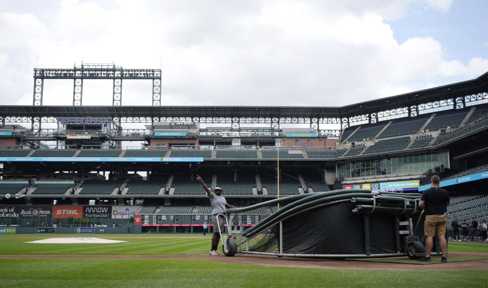 Grounds crew members pull down the batting cage after the postponement of a baseball game between the Colorado Rockies and the San Francisco Giants on Thursday, Sept. 14, 2023, in Denver. The game was rescheduled as part of a doubleheader Saturday. (AP Photo/David Zalubowski)