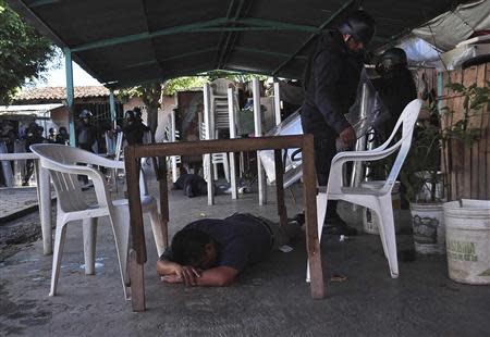 An inmate lies under a table as riot policemen inspect an area after a gunfight in the Tuxpan prison in Iguala, in the Mexican State of Guerrero January 3, 2014. REUTERS/Jesus Solano