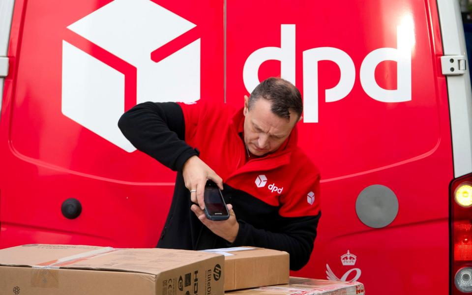 A DPD delivery driver scans a parcel in front of a DPD branded delivery van - Matthew Horwood/Getty Images